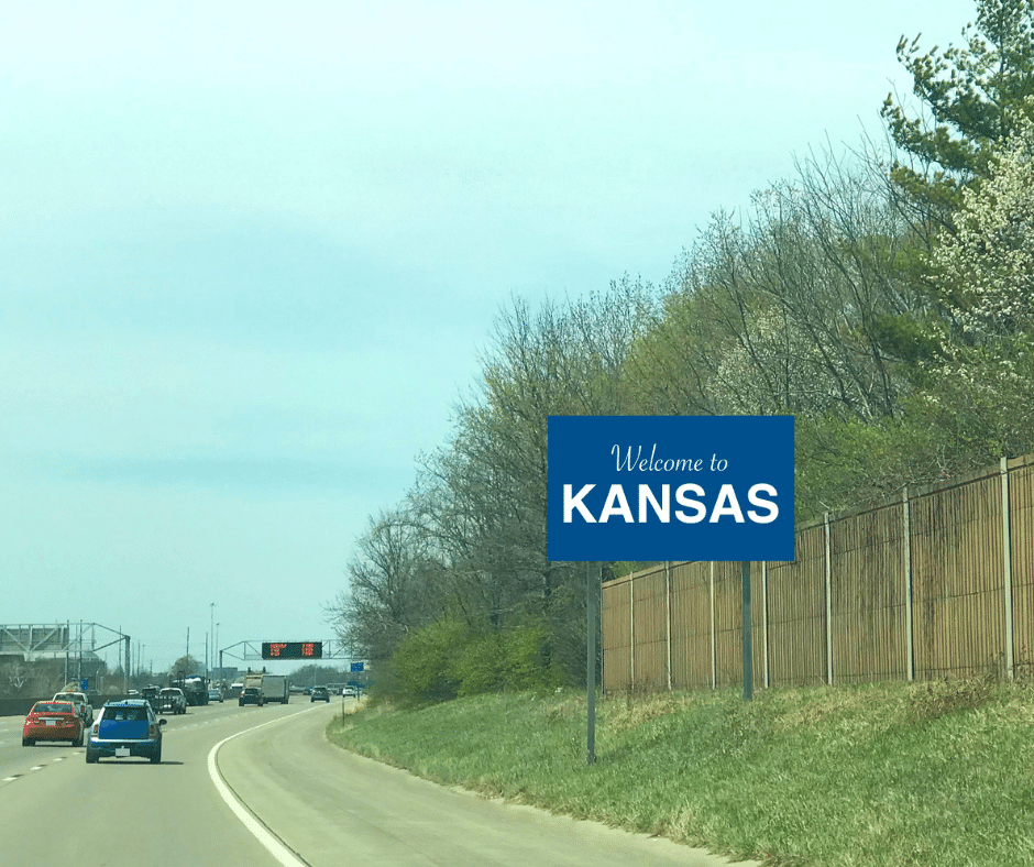 cars traveling on highway entering the state of Kansas