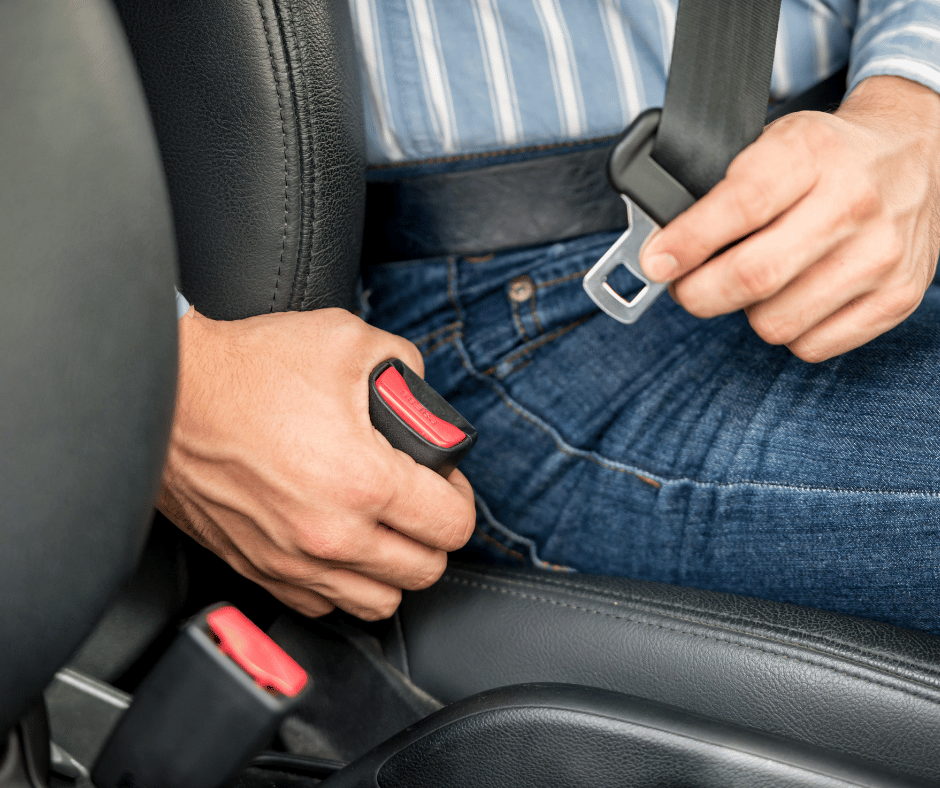 person fastening seatbelt while seated in car
